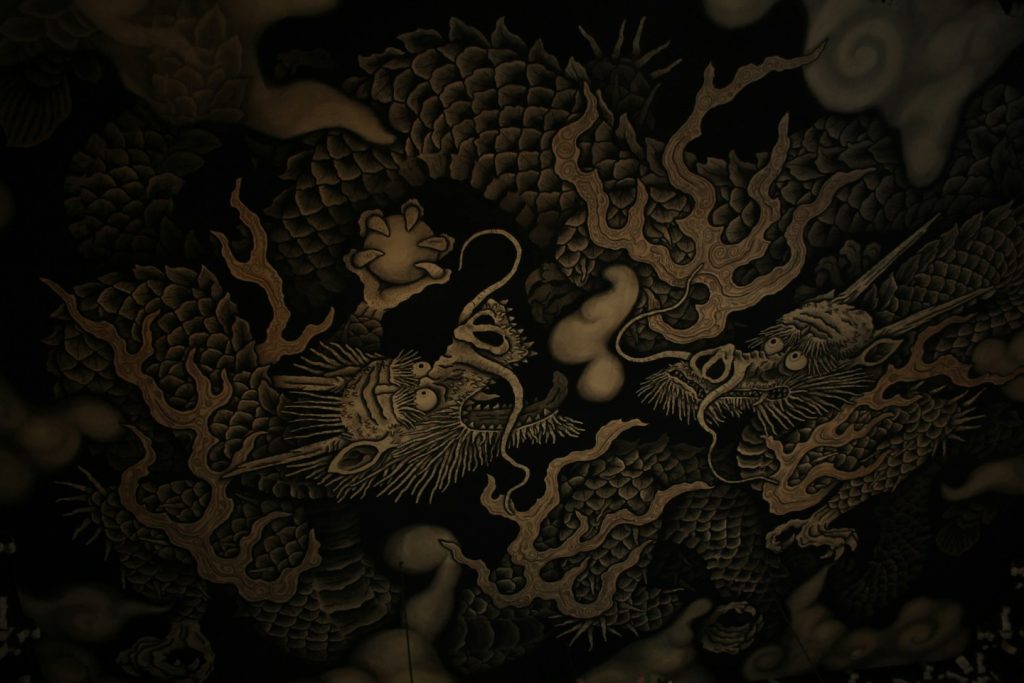 Deux dragons asiatiques peints à l'encre sur un plafond, écailles et crinières dorées sur fond sombre
